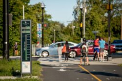 People walking and biking on a trail near a bicycle counter kiosk